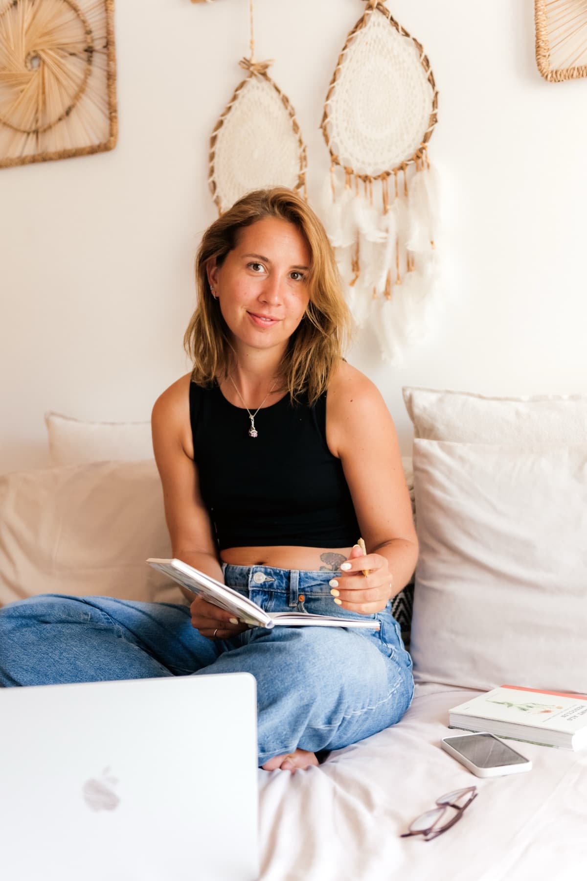 Kristel zit rustig op bed met een journal in haar handen en kijkt in de camera