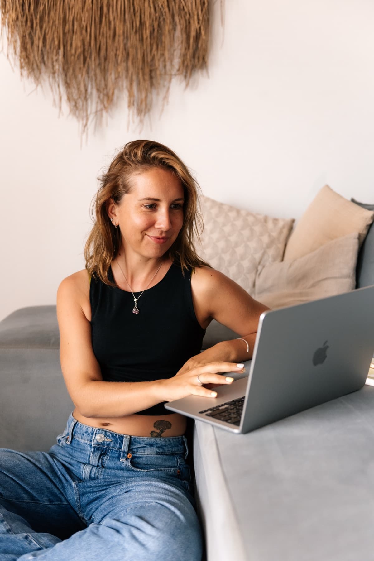 Kristel typt rustig op een laptop op de armleuning van een bank